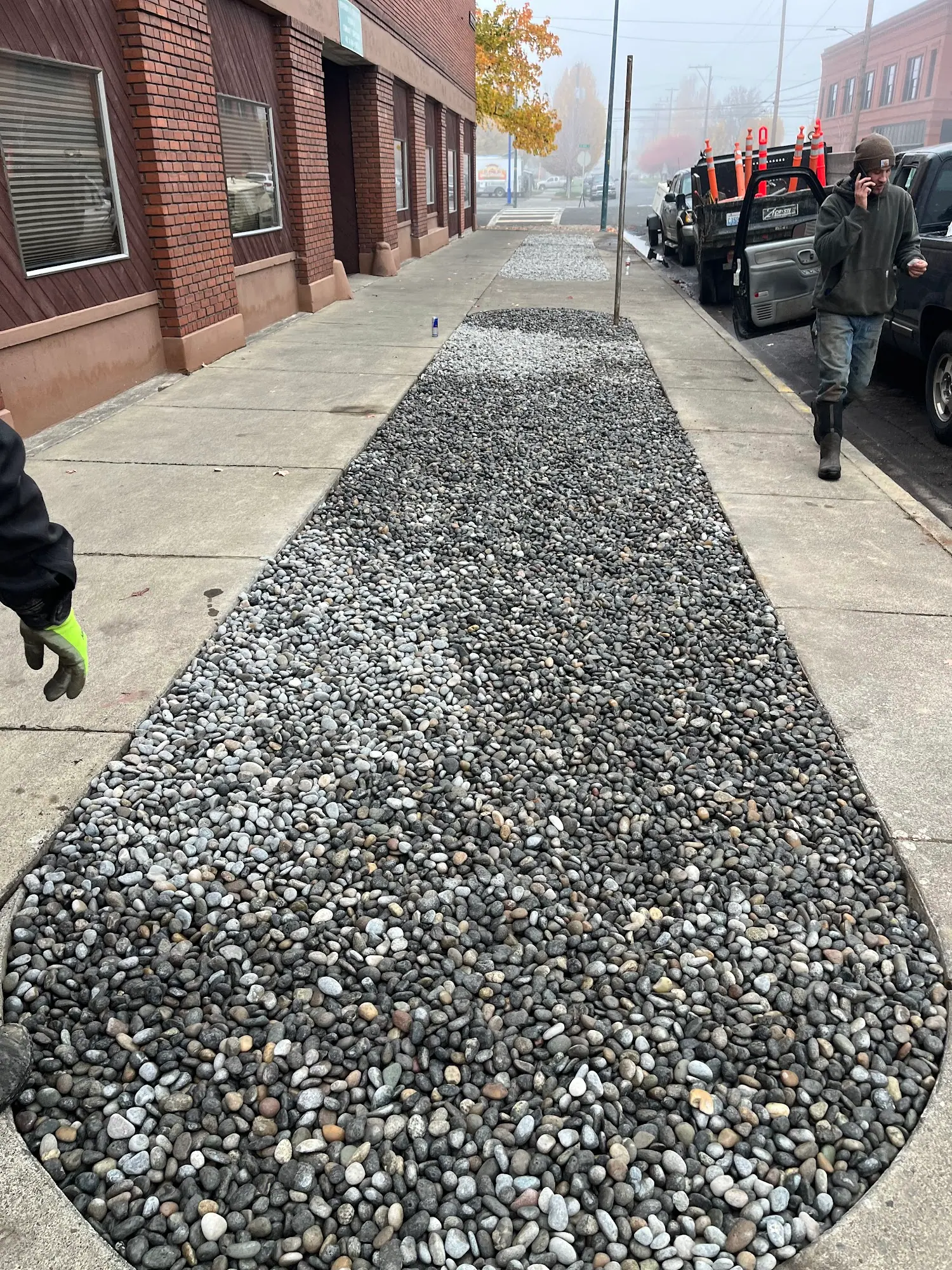 River-rock strip along a sidewalk beside a brick building